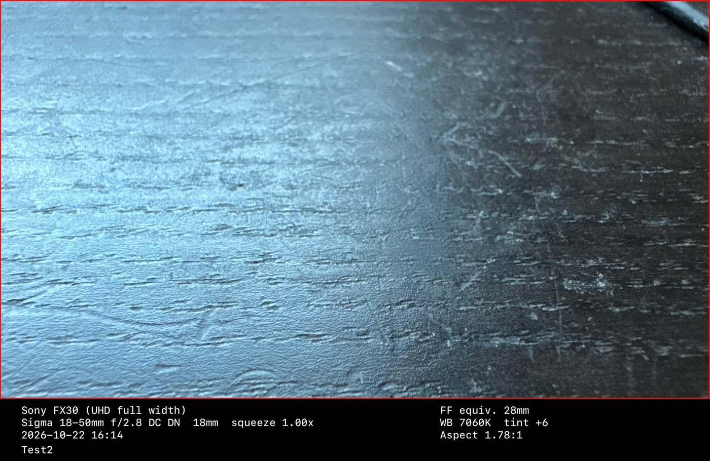 A still saved by FrameScout with a black strip underneath listing the camera, lens, focal length, date, white balance, aspect ratio and a note.